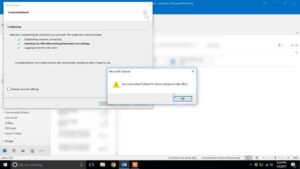 Microsoft Outlook configuration window showing progress and a warning message stating, "You must restart Outlook for these changes to take effect." The background displays the Outlook interface.